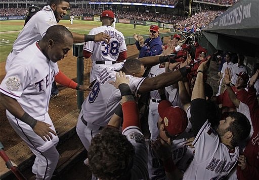 Texas Rangers' Adrian Beltre (29) is swarmed by teammates after hitting a home run during the sixth inning of Game 5 of baseball's World Series against the St. Louis Cardinals Monday, Oct. 24, 2011, in Arlington, Texas. 