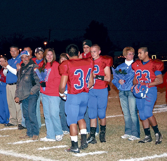Michele and Shawn Merrill, center, are presented a helmet by senior members of the Pinto football team (Walter Juarez (34), Grant Burger (12) and Steven Arce (23)) Friday at Riley Field in memory of their son Matthew, a Pinto football player who died July 31, 2007. Matthew was a teammate of the now senior football players through seventh grade at California Middle School. In his memory, the Pintos wore Matthew's initials on the back of their helmets for Senior Night. 