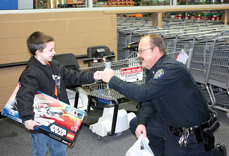 Lt. Bryan Reid of the Holts Summit Police Department helps a New Bloomfield boy buy presents at the Fulton Walmart during the annual Shop With A Cop event held Dec. 11, 2010.