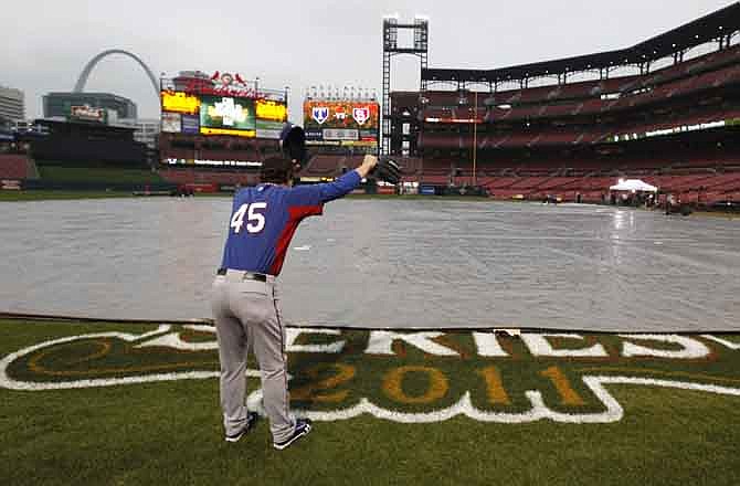 Texas Rangers' Derek Holland yells across a covered infield at Busch Stadium Wednesday, Oct. 26, 2011, in St. Louis, after officials announced that Game 6 of baseball's World Series is postponed due to rain. 