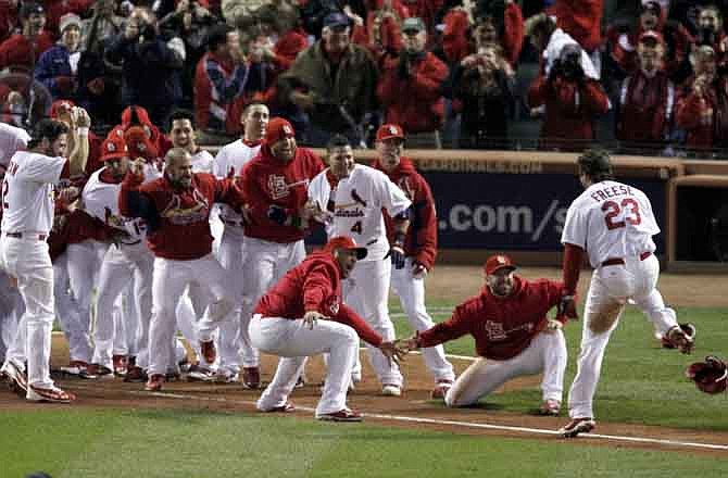 St. Louis Cardinals greet David Freese, right, at home after Freese hit a solo home run off a pitch by Texas Rangers' Mark Lowe in the 11th inning to win Game 6 of baseball's World Series 10-9, Thursday, Oct. 27, 2011, in St. Louis. The series is tied 3-3.