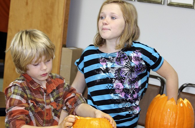 Wyatt Prosch, 7, carves pumpkins with his cousin, Anna Stubinger, after spending the afternoon filling treat bags to hand out at their church's trunk-or-treat. 