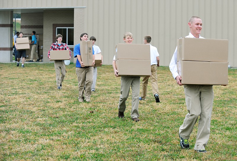 Kyle Maddox, in front, and several other students from Calvary Lutheran High School carry boxes of cookbooks to a storage shed where they'll be held until dispersed. As a fundraiser, the school is selling the books in several different local outlets, including area Lutheran churches and Calvary's Gift Shop on Washington Street. 