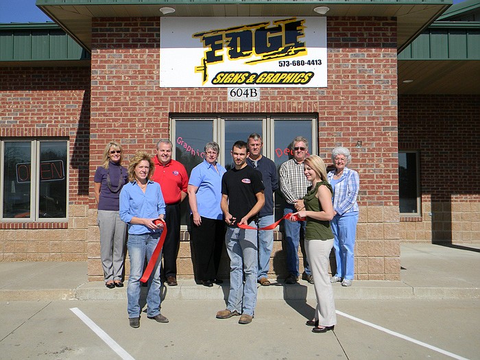 Members of the California Area Chamber of Commerce, family and friends help Edge Signs and Graphics Owner Andy Korte cut the ribbon on his new business.