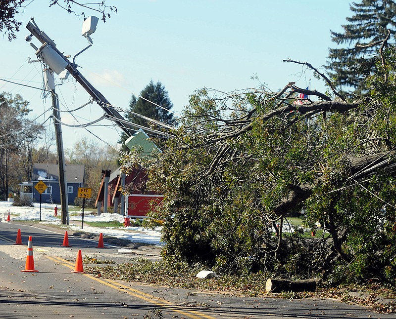 A snapped utility pole leans over the road Friday as the result of a fallen tree on the power lines in Enfield. Six days into an epic power outage that still has roughly 300,000 Connecticut residents in the dark, tempers are snapping as fast as the snow-laden branches that brought down wires across the region.