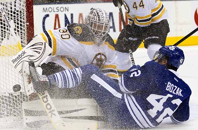 Toronto Maple Leafs center Tyler Bozak (42) crashes into Boston Bruins goaltender Tim Thomas who makes a save during second-period NHL hockey game action in Toronto, Saturday, Nov. 5, 2011.