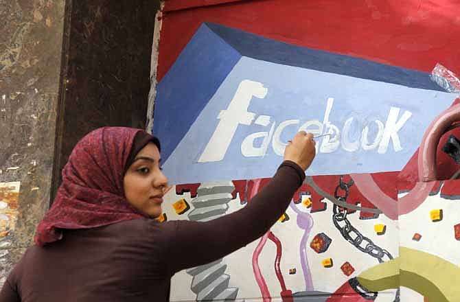 In this March 30, 2011, file photo. an art student from the University of Helwan paints the Facebook logo on a mural commemorating the revolution that overthrew Hosni Mubarak in the Zamalek neighborhood of Cairo, Egypt. Working at undisclosed locations in the USA, the team from the CIA's Open Source Center pores daily over tweets, Facebook, newspapers, TV news channels, local radio stations, Internet chat rooms - anything overseas that anyone can access, and contribute to, openly.