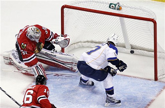 Blues defender Patrik Berglund (left), tries to control the puck as teammate Roman Polak (46) holds down Blackhawks forward Marian Hossa, during Tuesday's game in St. Louis.