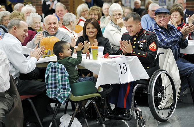 Lance Cpl. Tyler Huffman, center right, and his wife, Mellisa, clap with their son, Matthew, 2, during the Jefferson City High School Ambassador Club's Veterans' Appreciation Night in the high school cafeteria. Later in the evening, the details of a plan to help the Huffman family build an accessible house were announced.