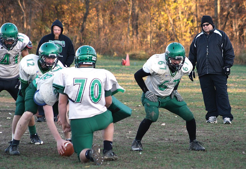 North Callaway head coach Mike Emmons (right) looks on as junior quarterback Jake Haubner (12) runs the Thunderbirds' first-team offense during Thursday afternoon's practice at the high school in Kingdom City. North Callaway (8-4) - coming off a 24-0 sectional home win over Southern Boone on Monday night - hosts No. 3 School of the Osage (12-0) in the Class 3 quarterfinals at 1:30 p.m. Saturday.