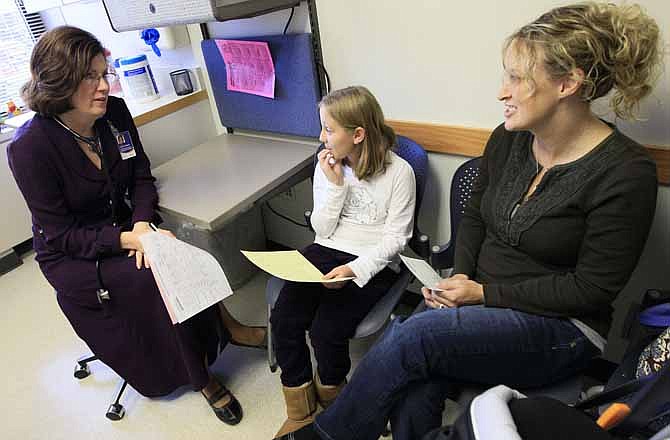 In this Tuesday, Nov. 1, 2011 photo, Dr. Elaine Urbina, left, goes over test results with Joscelyn Benninghoff, center, 10, and her mother, Elizabeth Duruz, at Children's Hospital in Cincinnati. Benninghoff is taking medication to control her cholesterol. In new guidelines released Friday, Nov. 11, 2011, doctors are recommending that every child be tested for high cholesterol by around age 10 to prevent heart disease later in life.