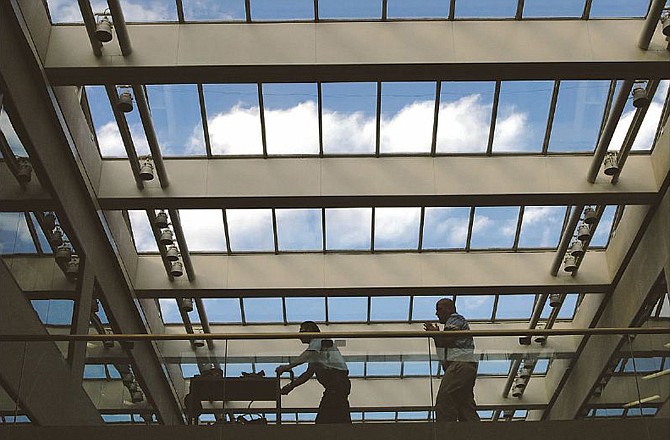 In this file photo, workers cross a seventh-floor walkway under a bright blue sky Tuesday morning, Nov. 10, 2011, in the atrium of the Harry S Truman State Office Building in Jefferson City.