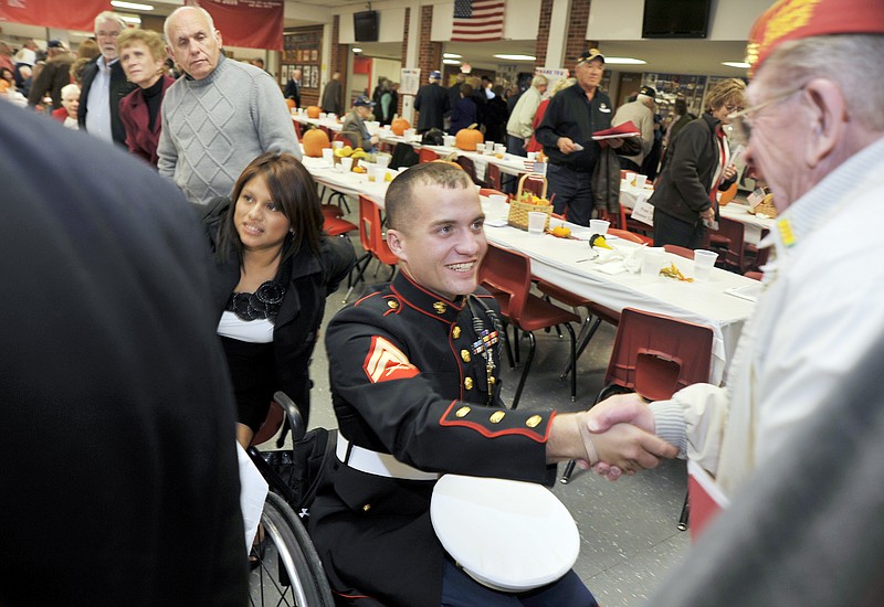 Lance Cpl. Tyler Huffman, center greets well-wishers as the Jefferson City High School's Ambassador Club's Veteran's Appreciation Night winds up Nov. 10, in the high school cafeteria. Details of  a plan to help the Huffman family build an accessible house were announced during the event. Huffman's wife, Mellisa, is at center left.