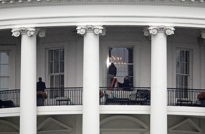 Law enforcement officers photograph a window Wednesday at the White House as seen from the South Lawn.