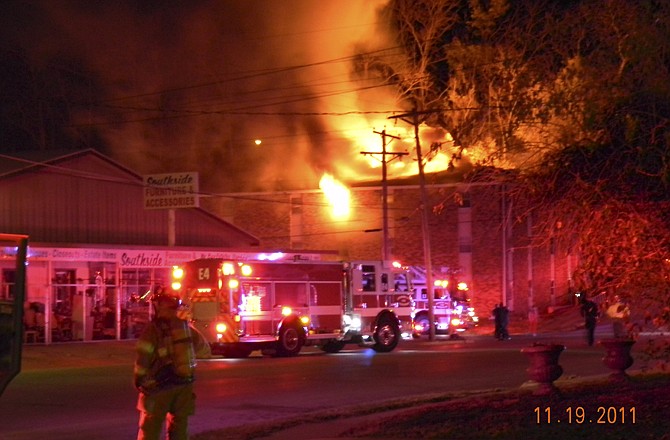 A firefighter stands facing an early Saturday morning blaze consuming an apartment building at the corner of Dunklin and Mulberry streets in Jefferson City.