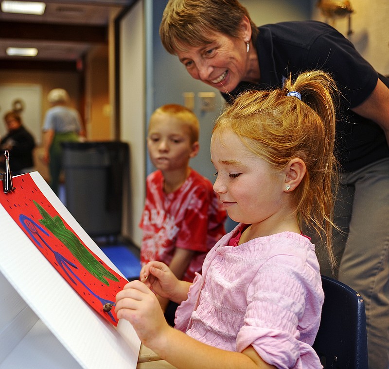 Lauren Peterson, 6, gives her artwork a unique look by painting with a bergamot seed head under the watchful eye of Assistant Nature Center Manager Robin Grumm on Friday during a holiday shopping alternatives - decorating naturally event at Runge Nature Center.