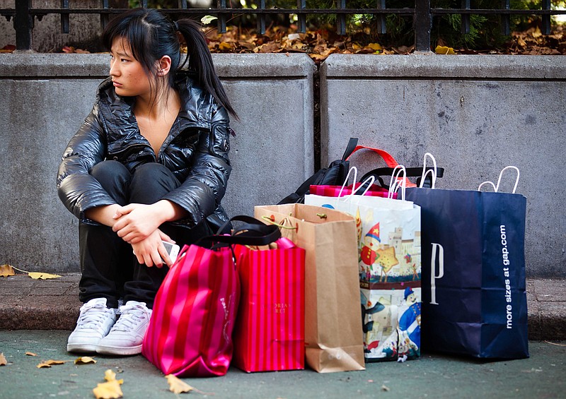 A consumer takes a break with her bags in Herald Square during the busiest shopping day of the year Friday in New York. 