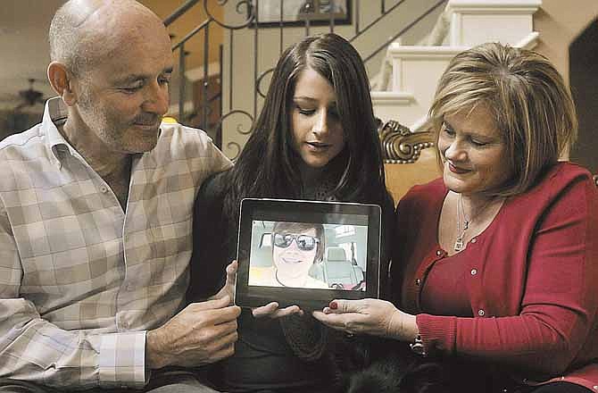 Mark, left, Sara, center, and Trish Norton look at a still from one of Will Norton's YouTube videos in Joplin Mo. Will Norton was headed home from his high school graduation when he was sucked away by a deadly tornado on May 22, 2011. (AP Photo/Roger Nomer/The Globe)