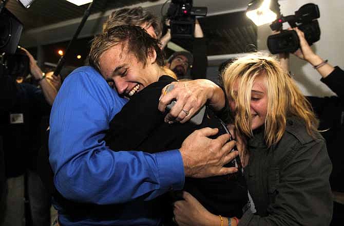 Derrik Sweeney, center, gets hugs from his father Kevin Sweeney, left, and sister Ashley, right, after Derrik arrived at Lambert-St. Louis International Airport Saturday, Nov. 26, 2011, in St. Louis.