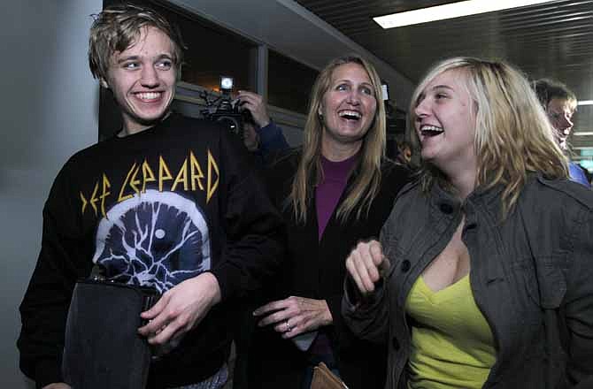 Derrik Sweeney, 19, of Jefferson City, Mo., smiles as he walks with his mother, Joy Sweeney, center, and sister Ashley Sweeney after arriving at Lambert-St. Louis International Airport Saturday, Nov. 26, 2011, in St. Louis. Derrik Sweeney and two other American students were arrested on the roof of a university building near Tahrir Square in Cairo last Sunday, accused of throwing firebombs at security forces fighting with protesters. On Thursday, a court ordered the three to be released.