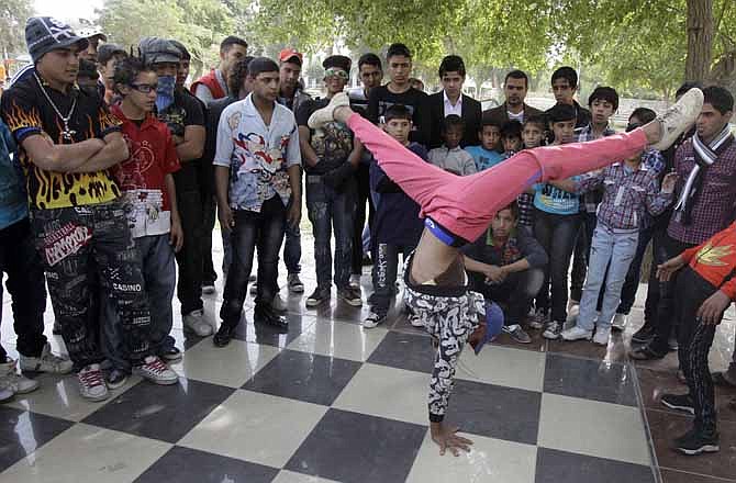 In this Thursday, Nov. 10, 2011 photo, an Iraqi boy dances to hip hop music in Baghdad, Iraq. After more than eight years in Iraq, the departing American military's legacy includes a fledgling democracy, bitter memories of war, and for the nation's youth, rap music, tattoos and slang.