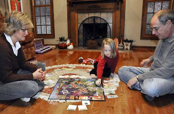 Four-year old Mia Meyers moves her piece around the board as she plays the Disney version of Monopoly with her parents, Abbe and Ed Meyers.