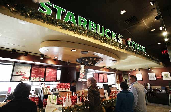 In this Nov. 19, 2011 photo, customers line up for hot drinks at Starbucks, in New York. The way Americans are chomping Big Macs, lacing up Air Jordans and gulping peppermint mochas in this abysmal economy, you'd think they're taking advantage of big holiday discounts.