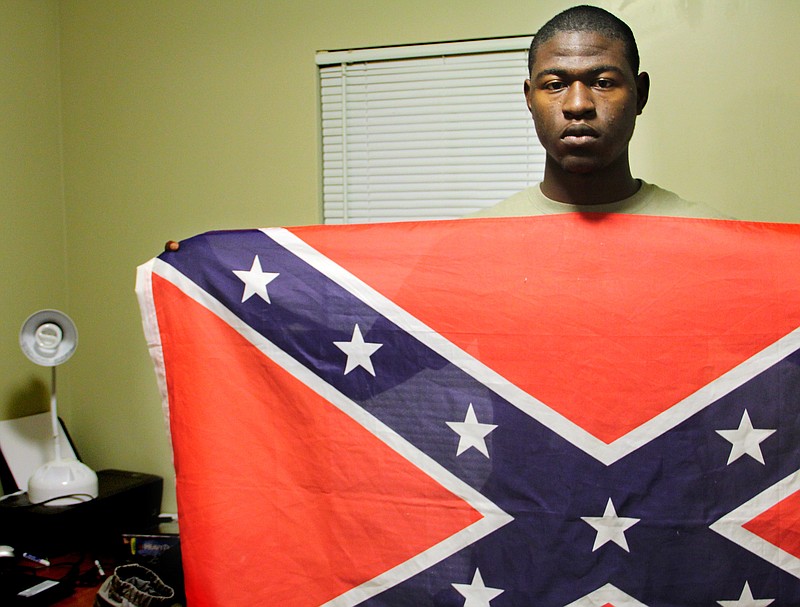 Byron Thomas, 19, a student at USCB holds a Confederate battle flag in his dormitory room Wednesday in Okatie, S.C. Byron Thomas says a class research project made him realize the flag's real meaning has been hijacked.