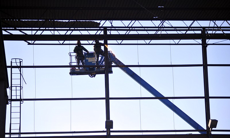 Union ironworkers Neil Schlup, left, and Paul Schlup, no relation, from A & H, of Columbia, torch the old main crane way so it can be dismantled Wednesday morning at DeLong's Inc. on Dix Road. The company is replacing the 50-year-old crane with a new, larger model that will increase their lifting capacity to 50 tons. One new crane has already been installed and a third will be added next year.