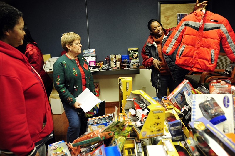In this Dec. 6, 2011 photo, Jennifer McKae, right, asks her mother, Wilma Jones, left, if she thinks the coat would fit one of McKae's children at the Samaritan Center. Volunteer Bev Buschmann helps McKae shop, center. The Santa's Workshop program serves the center's established client families with children younger than 13 years old.