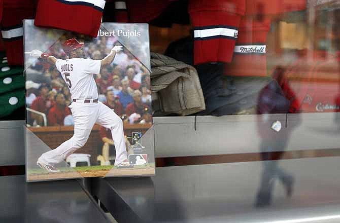 A person is reflected in the window of a store selling St. Louis Cardinals merchandise, displaying a photo of baseball player Albert Pujols, Thursday, Dec. 8, 2011, in St. Louis. Three-time National League MVP Albert Pujols agreed Thursday to a $254 million, 10-year contract with the Los Angeles Angels. 