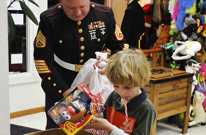 Xander Schmid, 5, gets some help from Marine Joe McGrail as he donated toys to the Marine Corp League's Toys for Tots program at Samuel's Tuxedos and Gifts.