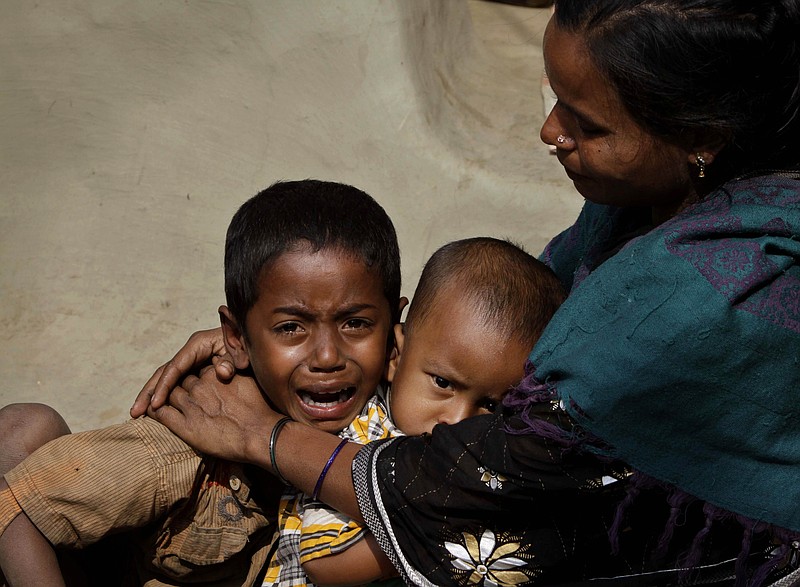A woman whose husband died after drinking toxic liquor tries to console her children Thursday at a hospital in Diamond Harbour, near Kolkata, India. 