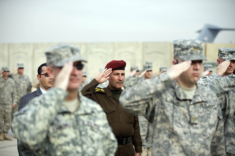 An Iraqi officer, center, and US Army soldiers salute during ceremonies Thursday marking the end of the U.S. military mission in Baghdad, Iraq. 