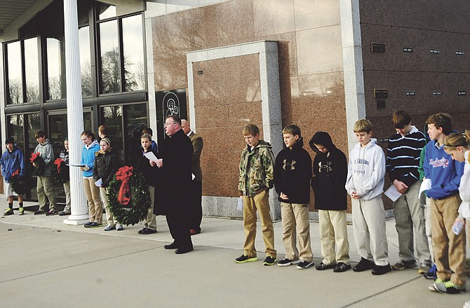 Fr. Greg Meystrik delivers the opening blessing at a wreath ceremony organized by the seventh grade students of St. Stanislaus School Thursday morning, Dec. 15, 2011, at the parish cemetery in Wardsville, Mo. The students collected money to purchase wreaths to honor the 60 veterans buried there. 