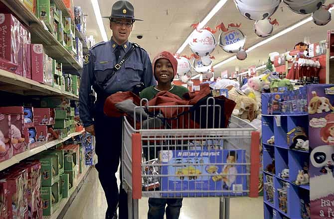 Missouri Highway Patrol Lt. Steve Frisbie, left, walks the toy aisles in the Jefferson City Kmart while helping Jaughn Robinson pick out his Christmas gifts during the annual Operation T.O.Y.S. on Saturday morning.