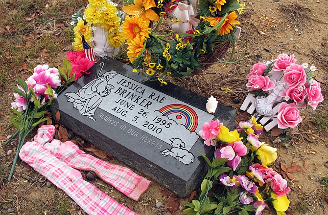 Bright, knee-high socks and wreaths of flowers adorn Jessica Brinker's headstone at a Catholic cemetery in St. James.
