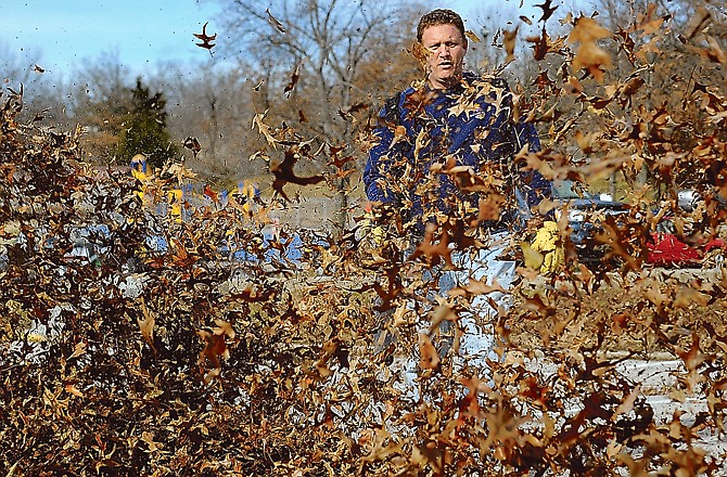 Andrew Smith clears the parking lot of leaves as he and the rest of the Trinity Dads help spruce up the grounds at Trinity Lutheran School on Saturday.