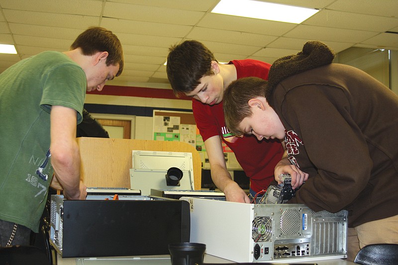(From left) Jordan Gonterman, senior, Nate Eichman, sophomore, and Thomas Palmer, sophomore, work on refurbishing used computers Monday at North Callaway High School.