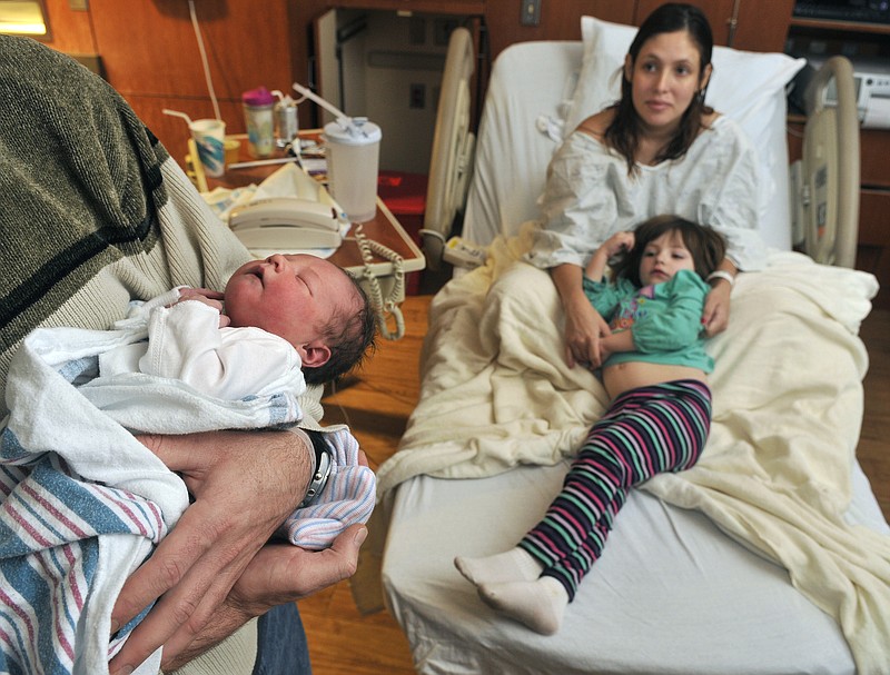 Russell LaFevre, left, holds his newborn daughter Joanna Mallory LaFevre while his wife Elizabeth LaFevre, holds their other daughter Renee, 3, and rests Tuesday at St. Vincent Hospital in Santa Fe, N.M.