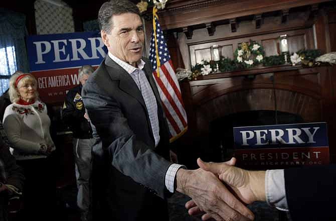 In this Dec. 14, 2011 file photo, Republican presidential candidate, Texas Gov. Rick Perry shakes hands during a campaign stop at Bayliss Park Hall, in Council Bluffs, Iowa. 