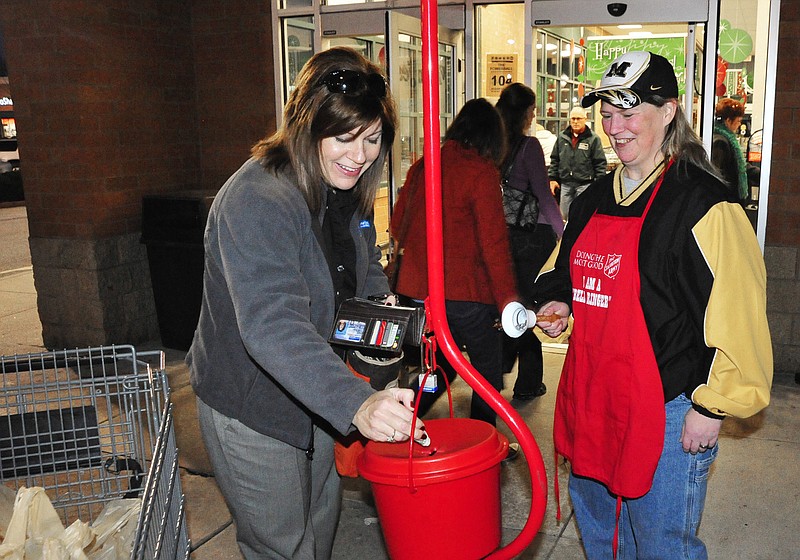 Janel Schnieders makes a donation Wednesday, Dec. 21, 2011 in the Salvation Army kettle at Schnucks. Julie Jordan, a volunteer from First Christian Church, was ringing the bell.