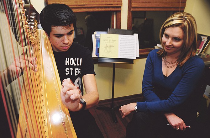 Ben Phelps, 16, practices his fingering during his Tuesday harp lesson with Ashley Nelson. Phelps, who has been playing the piano since first grade and the double bass since sixth, started taking harp lessons from Nelson in February 2010. 