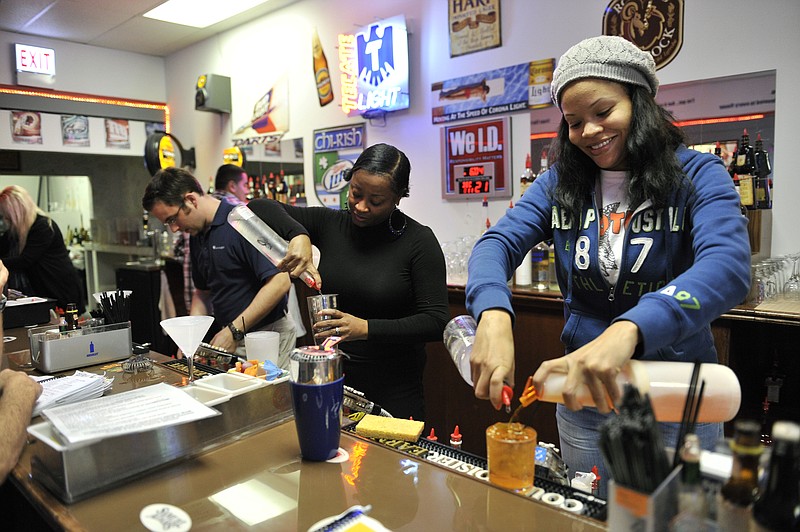 Sheree Johnson, right, and Tia Taylor practice mixing cocktails at the American Professional Bartender School.