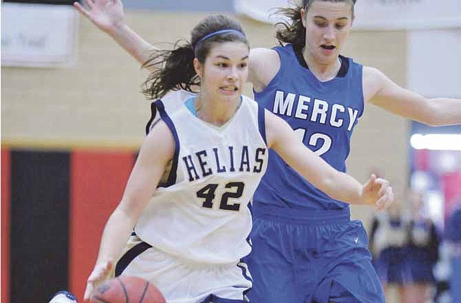 Taylor Hagenhoff of Helias drives past Emily Budde of Mother of Mercy during Friday's title game in the State Farm Holiday Hoops Invitational at Fleming Fieldhouse. 