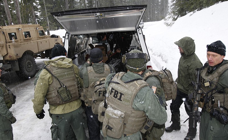 FBI SWAT team members load the body of Benjamin Colton Barnes into a vehicle Monday at Mount Rainier National Park in Washington state. Barnes' body was recovered from a creek bed Monday, after he allegedly shot and killed a park ranger Sunday. 