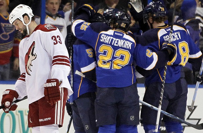 Adrian Aucoin of the Coyotes skaes past as the Blues congratulate teammate Jamie Langenbrunner for his first-period goal in Tuesday night's game in St. Louis.