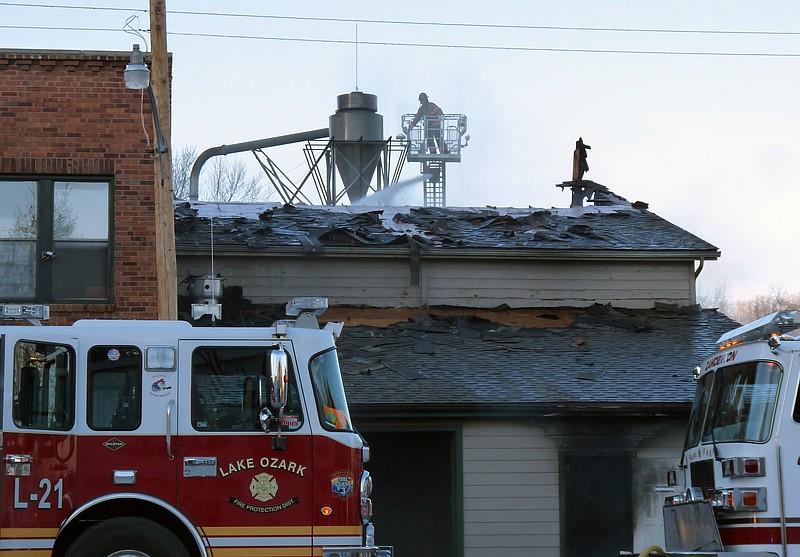 A firefighter sprays water onto hot spots inside a building destroyed Thursday at the Woodland Scenic's manufacturing plant in Linn Creek.