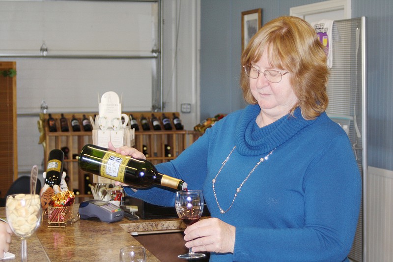 Regina Ruppert pours a sample of Touch of Black N Gold, a black current merlot, at Serenity Valley Winery Saturday morning. Ruppert and her husband, Lee, moved their winery to the Millersburg area from O'Fallon in November.