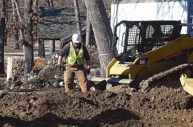 State Fair Community College student Taylor Glenn wades through the mud to sort and separate stones taken from the foundation of the Camp Pin Oak Lodge dining hall.